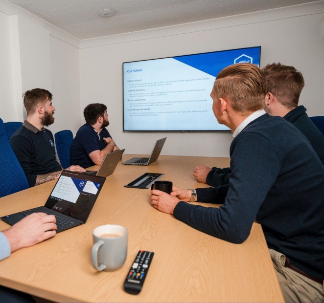 Team members participating in a cyber security awareness and training session, reviewing company values and security practices on a large presentation screen in a meeting room.