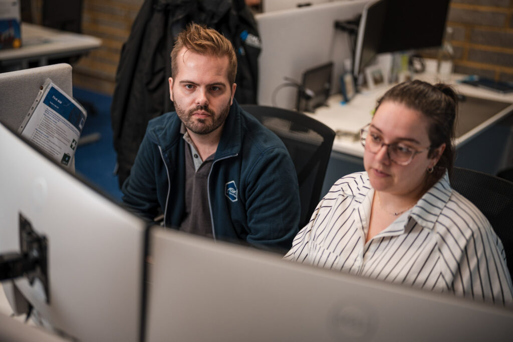 IT support professionals monitoring business systems and network performance from a modern office workspace, delivering proactive managed IT services and cyber security support.