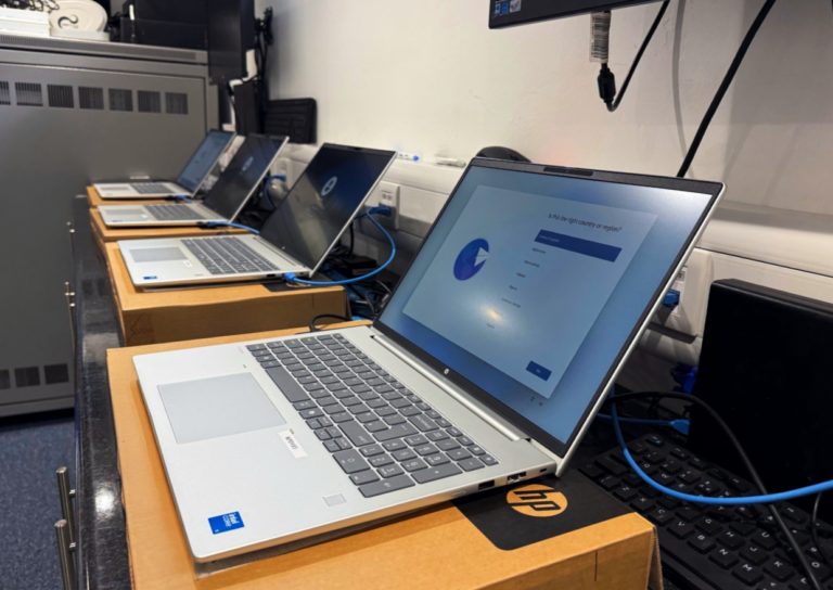 Row of HP laptops being configured in a school IT environment using Microsoft Intune for Education, showcasing device deployment, endpoint management, and classroom technology administration.