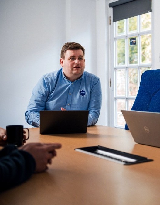 IT professional leading a business cybersecurity meeting with laptops, discussing password management, data protection, team security policies, and cybersecurity best practices.